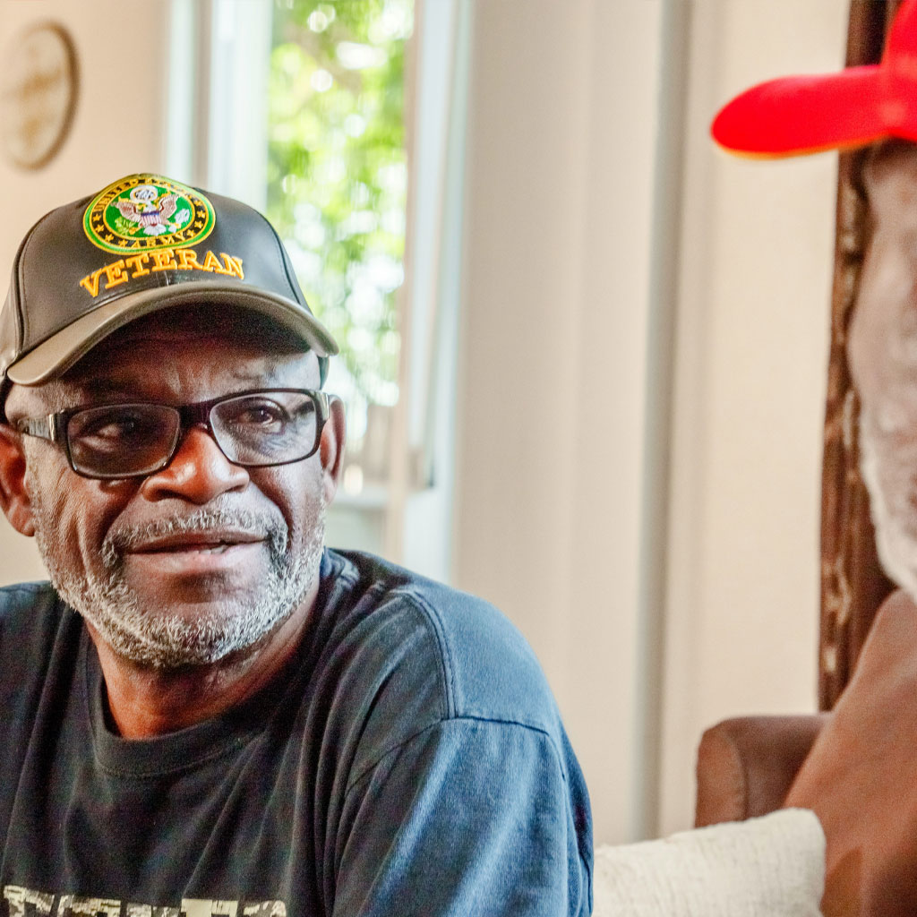 Man in Veteran cap smiling while talking.